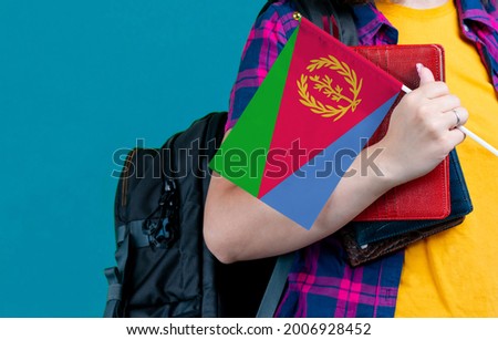 Young girl with school stuff holds in hand Eritrea flag close up