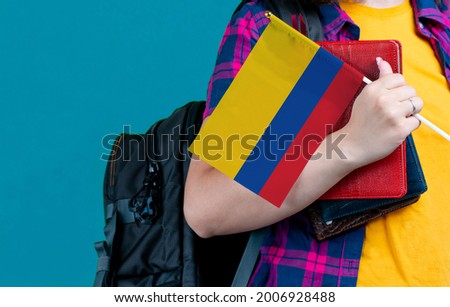 Young girl with school stuff holds in hand Colombia flag close up