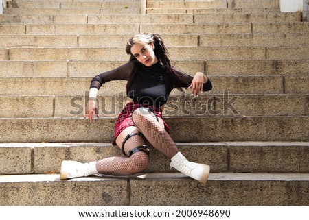 pretty young girl in punk style sitting on a staircase as if she were a rag doll lolita.