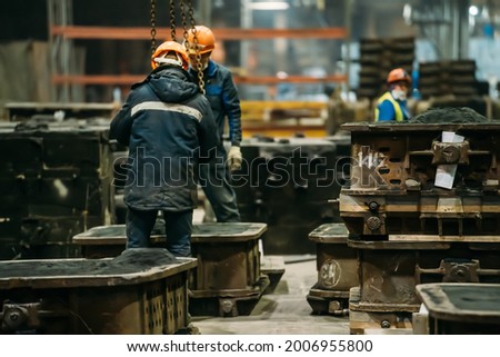 Unrecognizable workers with molds for metal cast in metallurgical plant foundry. Heavy industry