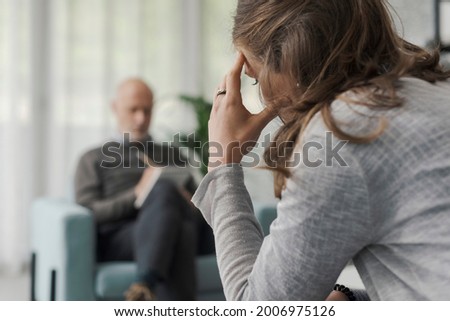 Professional therapist writing notes while listening to his patient during a psychotherapy session Royalty-Free Stock Photo #2006975126