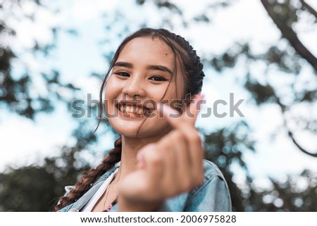Portrait of a cute and beaming Filipina teenager making a heart finger gesture. A K-pop fan. Royalty-Free Stock Photo #2006975828