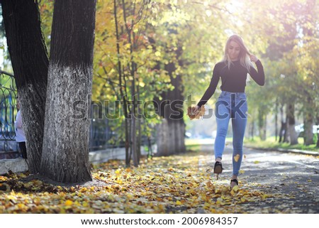 Young beautiful girl for a walk in a summer park. Leaf fall in city park. Beginning of autumn. September.