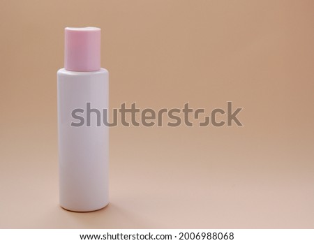 Natural beauty cosmetic bottles white mockup with pink cap cosmetic product for skin care on beige background. Levitation cosmetic white lotion bottles.