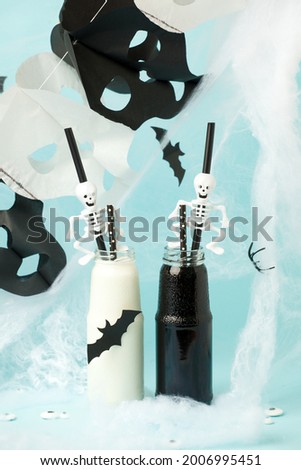 Halloween Pumpkin Cocktail Food Concept, Glass Jar with Cobweb, Black Bats and Spiders on Blue background, Spooky Toxic Drink, seasonal menu concept, Home party funny food, idea for kids