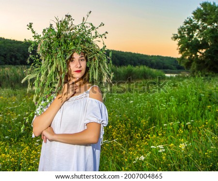 Portrait of a girl at sunset. A girl in light clothes and with a wreath on her head against the background of nature. 