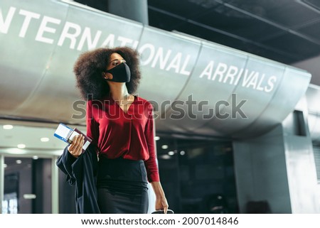 Female business traveler wearing face mask walking in airport terminal. Businesswoman on arrived at international airport during pandemic. Royalty-Free Stock Photo #2007014846