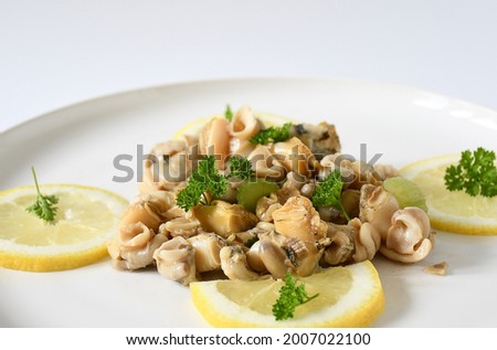 Fresh top view whelks's cook or sea snails in a white plate, piece of  lemon ,persil on white background.Food marine gastropod simple various in asia, europe kitchen, seafood concept. Selective focus. Royalty-Free Stock Photo #2007022100