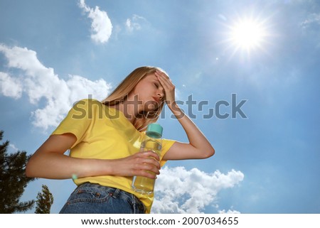Woman with bottle of water suffering from heat stroke outdoors Royalty-Free Stock Photo #2007034655
