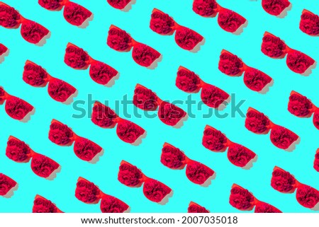 Creative pattern made of red sunglasses with rose buds on blue background. Summer fashion concept. Top view. Flat lay