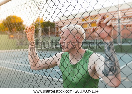 albino blond man, sportsman on a fence resting