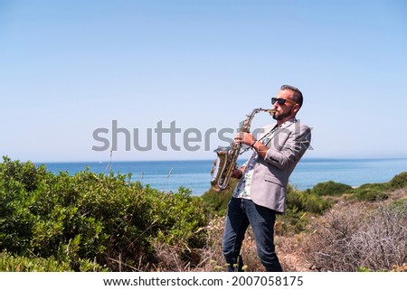 saxophonist playing the saxophone on a walkway near the beach