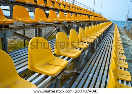 Yellow plastic seats on the podium of a small sports field.