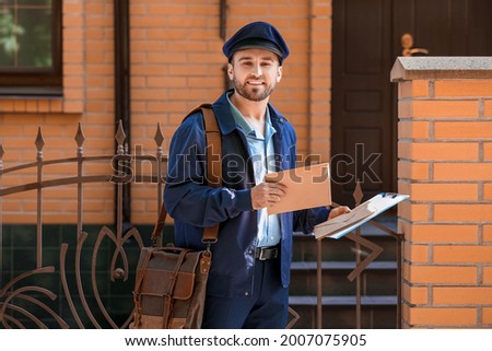 Handsome young postman with letters outdoors Royalty-Free Stock Photo #2007075905