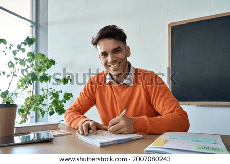 Young happy Hispanic Indian latin student gen z hipster having virtual distant class course with teacher writing notes looking at camera. Education technologies concept. Webcam view portrait. Royalty-Free Stock Photo #2007080243