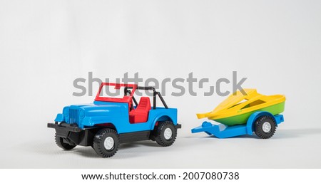 Plastic toy multicolored cars isolated on white background. A car with a motor boat on a trailer.