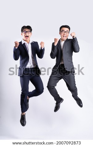 Two Asian businessmen jumping on white background