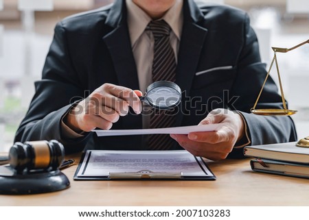 Attorney or judge sitting at  desk, holding magnifying glass and reading book. Businessman, business auditor, teacher, professor searching for information, fact-checking, law consulting professional 