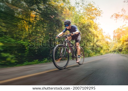 Cycling Mountain Bike Cycling MTB on the road shady with forest. Mountain biking athlete look at wild nature on mountain. Extreme Sport and MTB, mountain bike downhill of motion Concept. Royalty-Free Stock Photo #2007109295