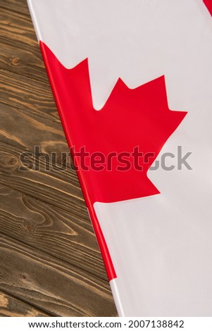 top view of canadian flag with red maple leaf on wooden surface