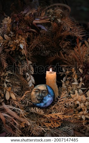 burning candle, moon amulet in dry autumn leaves on dark natural background. pagan, Wiccan, Slavic traditions. Witchcraft, esoteric spiritual practice. magic ritual. witch aesthetic. autumn equinox Royalty-Free Stock Photo #2007147485