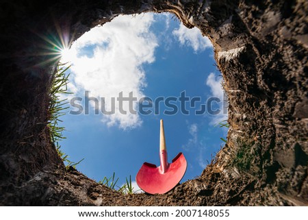 Looking up from hole in yard with shovel. Buried underground utilities, digging a hole and gardening concept Royalty-Free Stock Photo #2007148055