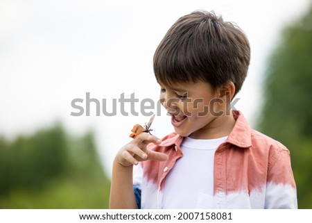 boy with butterfly on hand in the nature background 