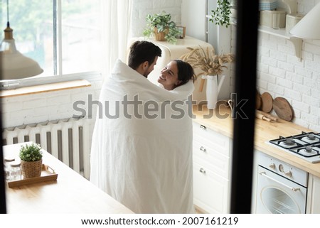 Loving man and woman standing in modern kitchen wrapped together in blanket smile look at each other enjoy conversation, above view. Romantic weekend, affection, relocation and cohabitation concept Royalty-Free Stock Photo #2007161219