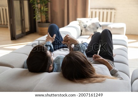 Couple in love holding hands relaxing lying on comfy modern sofa in warm cozy living room, enjoy conversation share dreams daydreaming together about happy joint future, cohabitation. Tenancy concept Royalty-Free Stock Photo #2007161249