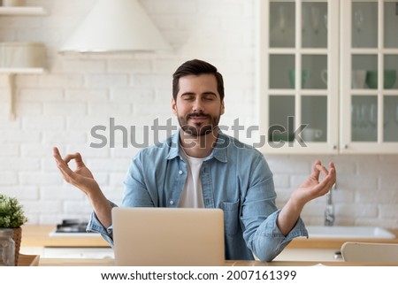 35s handsome man take break from telecommute on laptop, make meditation practice sit in kitchen relaxing with eyes closed. No stress, good life habits, fatigue tiredness relief, yoga lifestyle concept Royalty-Free Stock Photo #2007161399
