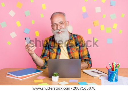 Portrait of elderly retired pensioner cheery grey-hared man using laptop gadget development isolated over pink pastel color background