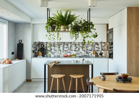 Stylish kitchen interior design with dining space. Workspace with kitchen accessories on the back ground. Creative walls with woode pannels. Minimalistic style an plant love concept.  Royalty-Free Stock Photo #2007171905