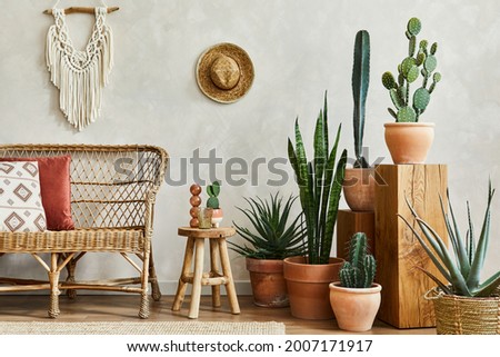 Stylish composition of cozy living room interior with copy space, lot of cacti and plants, wooden cubes and rattan accessories. Beige wall, carpet on the floor. Plants love concept. Template.