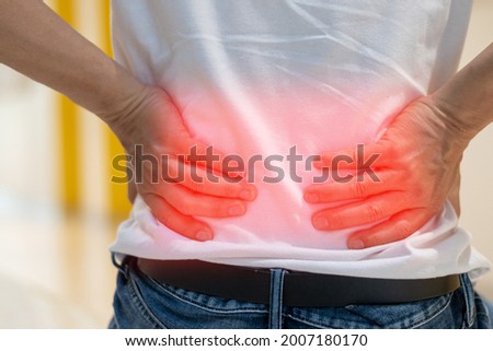 Man's hands on his back with red spot as suffering on backache. Male person sick from lower back pain from Herniated or slipped discs,Degenerative, sacroiliac joint, spinal stenosis, Pancreatic Cancer Royalty-Free Stock Photo #2007180170
