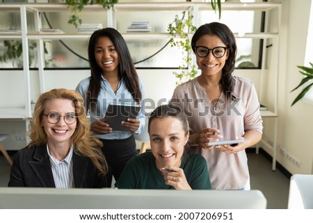 Portrait of diverse female business team at office workplace with computer and tablet. Multiethnic group of students, interns and older mentor meeting, smiling at camera in training center. Head shot