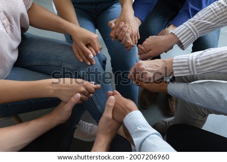 Group of anonymous addicted prayers holding hands, praying on therapy meeting, giving empathy, support, help, expressing compassion , trust, understanding, keeping community spirit. Close up Royalty-Free Stock Photo #2007206960