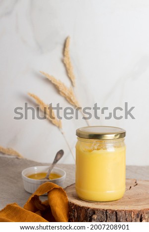 Indian ghee clarified butter desi in glass jar on wood slice.  Royalty-Free Stock Photo #2007208901