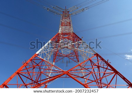 High-voltage electricity transmission tower under blue sky and white clouds . Power lines against the sky