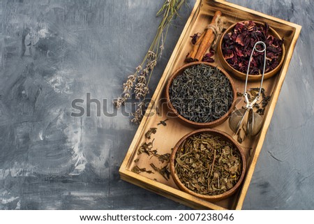 assortment of dry tea in wooden bowls and a teapot on a wooden surface. For the tea ceremony.