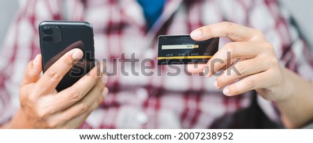 Close-up of a businessman’s hand holding credit card and using laptop at home. Businessman or entrepreneur working, online shopping, e-commerce, internet banking, working from home concept