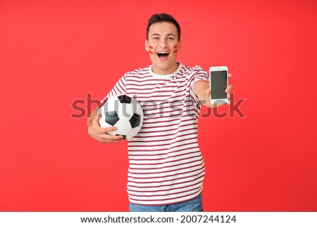 Happy man with soccer ball and mobile phone on color background. Concept of sports bet Royalty-Free Stock Photo #2007244124