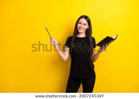 Photo of charming cheerful girl hold notepad look indicate pencil empty space isolated on yellow color background