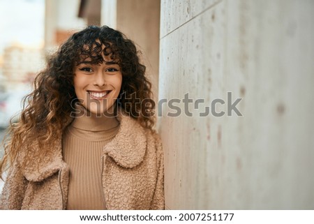 Young hispanic woman smiling happy standing at the city