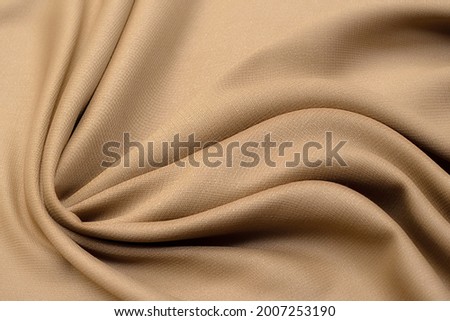 Abstract texture of natural beige or brown color fabric as concept background. Fabric texture of natural cotton or linen, silk or satin, wool or jersey textile material. Luxurious dark background. Royalty-Free Stock Photo #2007253190