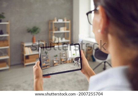 Woman who plans on selling her studio apartment taking photo of stylish decor in custom design living room interior on her smart tablet. Young blogger or house seller giving video tour around her home