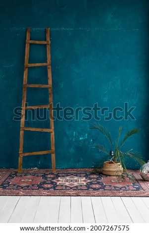 boho-style photo shoot area. dark, bright blue wall, plaster. carpet and wooden stairs