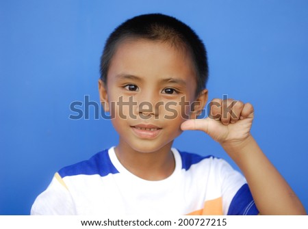 Little boy showing thumbs up gesture-blue background