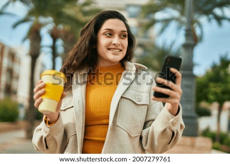 Young middle east woman using smartphone drinking coffee at the city.