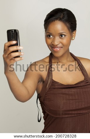 Young South African woman taking a picture of herself with her phone.