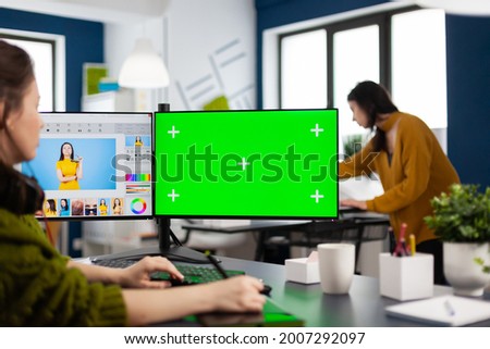 Creative woman retoucher editing assets in digital retouching program, working concentrated in photo production studio looking in computer with green screen, chroma key mockup isolated display.